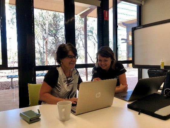 Two people smiling and looking at a laptop screen