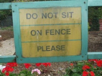 A sign that reads 'do no sit on fence please'