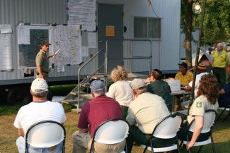 Person holding a lecture to people using a bulletin board