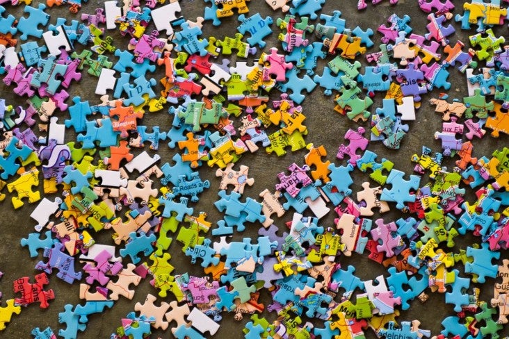 Many brightly coloured jigsaw pieces piled on a table